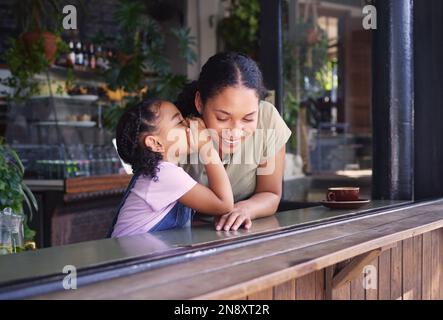 Secret, children and a black family in a coffee shop with a girl whispering in the ear of her mother. Kids, gossip and whisper with a secretive female Stock Photo