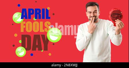 Laughing man with whoopee cushion on red background. April Fools' Day celebration Stock Photo