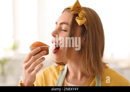 Female baker eating tasty cupcake in kitchen, closeup Stock Photo