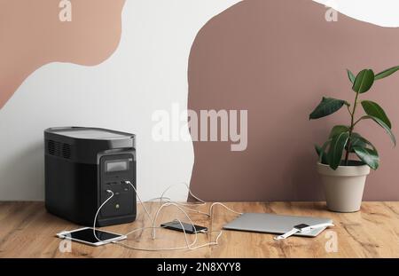 Portable power station charging gadgets near wall Stock Photo