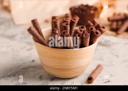 Bowl with delicious chocolate wafer rolls on beige background Stock Photo