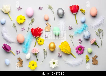 Composition with Easter eggs, feathers and different flowers on light background Stock Photo