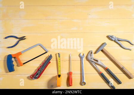 Screwdriver,hammer,tape measure and other working tools on yellow wooden background with copy space,industry engineer tool concept.still-life. Stock Photo