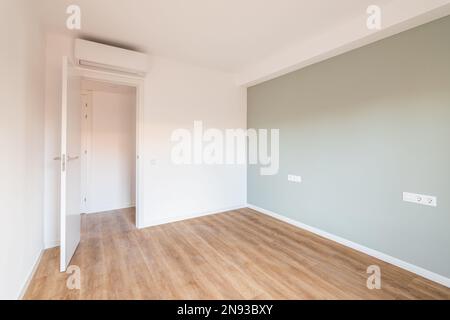 Bright spacious bedroom with parquet flooring. An open door from the room leading to a corridor with other rooms. Air conditioning above the door Stock Photo