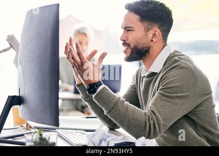 Why arent you working. a handsome young businessman sitting in the office and feeling irritated while using his computer. Stock Photo