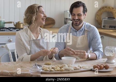 Cheerful couple in love in aprons baking in home kitchen Stock Photo
