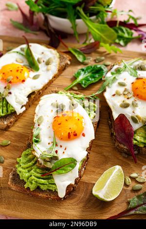 Egg and avocado toast, sandwiches with eggs and fresh greens. Healthy diet food Stock Photo