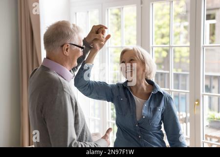 Cheerful elderly energetic couple in love dancing together at home Stock Photo