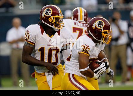 Washington Redskins quarterback Robert Griffin III (10) hands the ball off  to running back Evan Royster (35) in the first half of an NFL preseason  football game against the Chicago Bears in