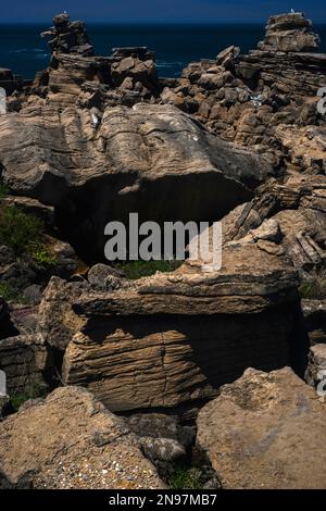 Tumbled and jumbled Early Jurassic layered rocks on the Cabo Carvoeiro cliffs near Peniche in Leiria District, central Portugal, with seagulls perched on the flat summits of stacks standing high above the Atlantic surf. Stock Photo