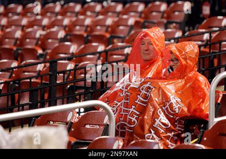 Baseball fans wearing ponchos wait during a rain delay prior to