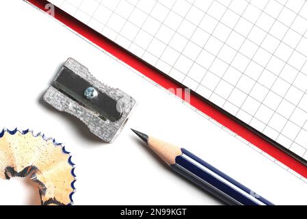 directly above close-up of pencil sharpener, pencil and notepad on white desk Stock Photo