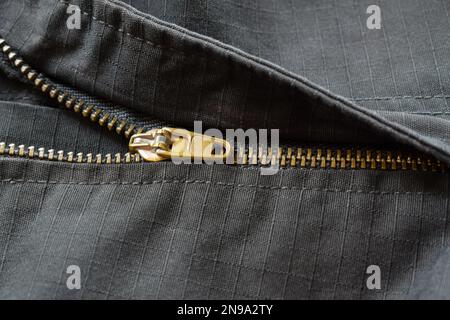 Close-up of half open gold zipper on black pants. Stock Photo