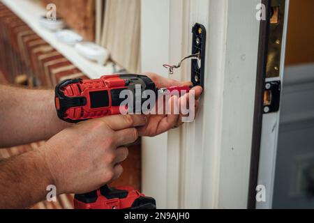 Man carpenter using drill to install door knob Stock Photo