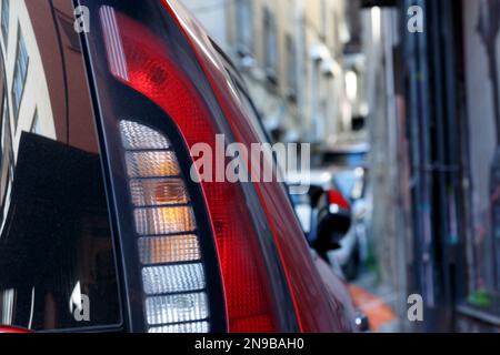 red car tail light with reflection of buildings on the street Stock Photo