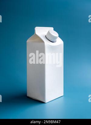 Mockup white milk box 1 liter with screw cap standing isolated on blue background, vertical style. Photo of white clear empty tall milk box with blank Stock Photo