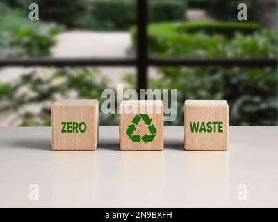 Environmental sustainability, ecology and recycling concept. Wooden cubes with the word zero waste and recycling symbol in front of a green garden win Stock Photo