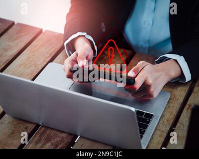 Virus alert. Red triangle, System hacked error sign, malware, attention danger symbol warning showing on smartphone while business person playing onli Stock Photo