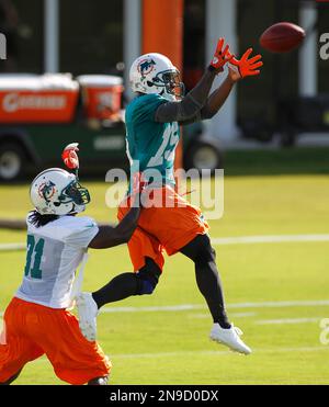 Miami Dolphins' Davone Bess (15) pulls on Chicago Bears' Charles Tillman  (33) jersey after Tillman intercepted a pass as Olin Kreutz (57) applies  pressure during a NFL football game in Miami, Thursday