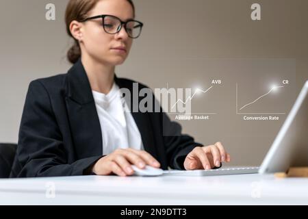 Businesswoman using keyboard and digital tablet analyzing retail kpi conversion rate and average basket rate. Stock Photo