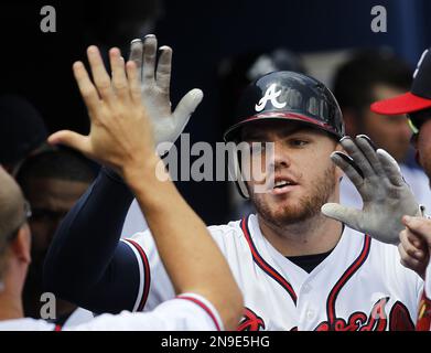 Atlanta Braves' Freddie Freeman is congratulated in the dugout after  scoring on Nick Markakis' groundout to second base during the first inning  of a baseball game against the Philadelphia Phillies, Sunday, June