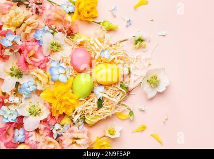 Easter composition with Spring Flowers and Easter eggs in nest on pastel pink background. Top view, copy space. Stock Photo