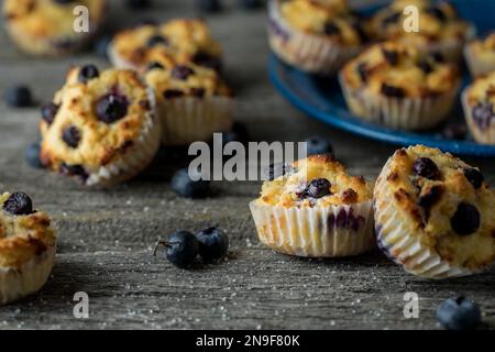 Several fresh homemade blueberry muffins scattered about on a rustic wood table. Stock Photo
