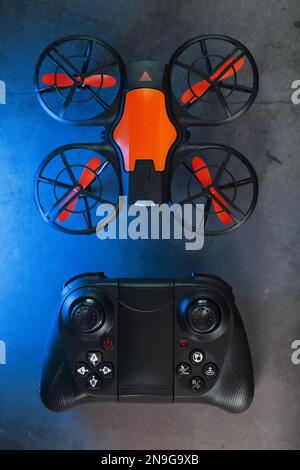 Quadcopter drone with joystick control and blue neon backlight, on a dark textured background Stock Photo