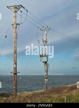 Two Pole mounted medium voltage connectors between underground and overhead connectors one with an electrical power transformer Stock Photo