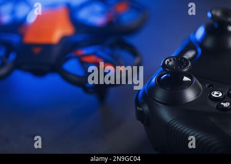 Quadcopter drone with joystick control and blue neon backlight, on a dark textured background Stock Photo
