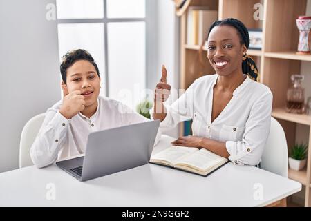 Young mother and son doing homework with laptop smiling happy and positive, thumb up doing excellent and approval sign Stock Photo