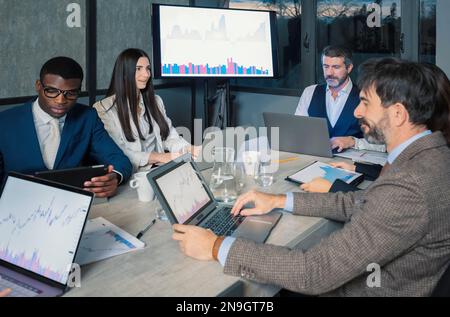 Young Smiling Business People on Meeting in Office. Group of Young Coworkers Sitting Together at Table in Modern Office. Business Team Working Togethe Stock Photo