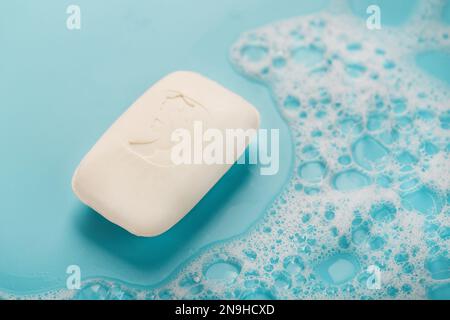 Scented white soap with a seahorse pattern with foam on a blue background Stock Photo