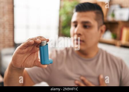 Young latin man using inhaler sitting on sofa at home Stock Photo