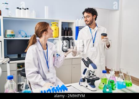 Man and woman scientist partners holding vr goggles and drinking coffee at laboratory Stock Photo