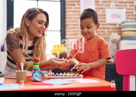 Teacher and toddler playing xylophone sitting on table at kindergarten Stock Photo