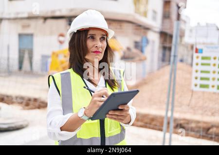 Young beautiful hispanic woman architect drawing on touchpad with relaxed expression at street Stock Photo