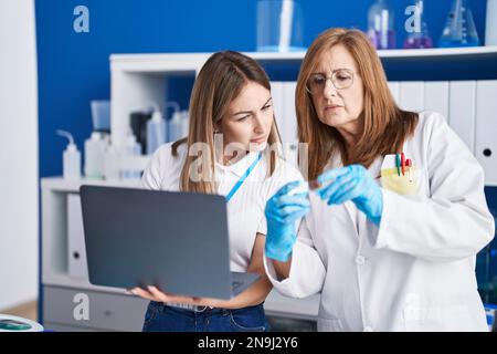 Mother and daughter scientists using laptop working at laboratory Stock Photo