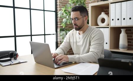 Young hispanic man business worker using laptop working at office Stock Photo