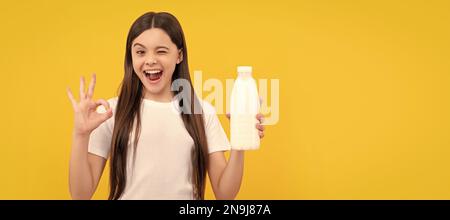 winking child hold dairy beverage product. teen girl going to drink milk. Horizontal poster of isolated child face, banner header, copy space Stock Photo