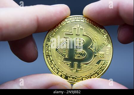 Bitcoin transfer concept from hand to hand. High quality photo. Finger hold bitcoin golden on black isolated. Hand hold gold bitcoin crypto digital mo Stock Photo