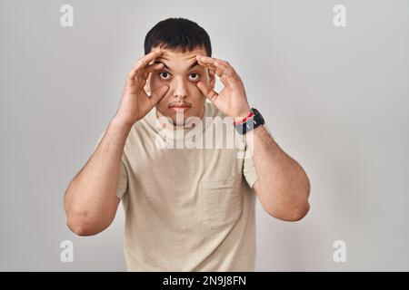 Young arab man wearing casual t shirt trying to open eyes with fingers, sleepy and tired for morning fatigue Stock Photo