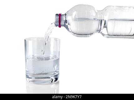 Clear and cool water poured in glass from 500ml pet plastic bottle, isolated on white with copy space Stock Photo