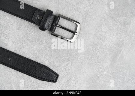 Black men leather belt with metal badge gray concrete background Stock Photo