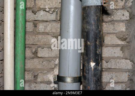 Sewer and water pipes fixed on a bricks with cement wall, plumbing fixing concept of water supply and sewer services, selective focus of the services Stock Photo