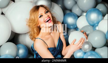 Beautiful girl among holding balloons. Woman among balloons. Dreams Come True. Enjoying the moment. Lady in blue. Surprise on holiday. Stock Photo