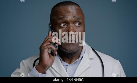 Portrait mature serious man talking on mobile phone focused puzzled confused professional doctor pediatrician therapist remotely communicates with Stock Photo