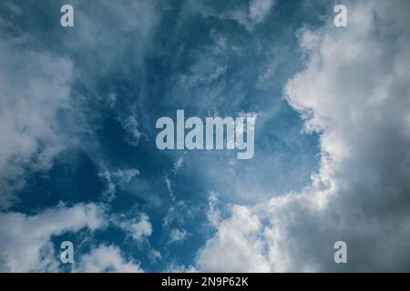 Intense blue sky with fluffy white and greyish storm clouds and intense midday light Stock Photo