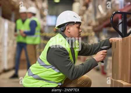Side view portrait of female worker scanning codes on boxes in storage warehouse Stock Photo