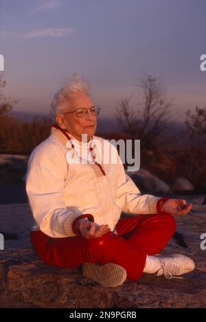 Older woman meditating on a mountaintop Stock Photo